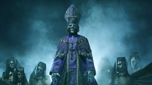 Een figuur in paarse religieuze gewaden met een schedelmasker staat centraal omgeven door andere gemaskerde figuren in een mistige omgeving met een spookachtige sfeer.